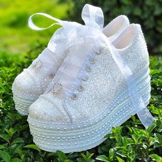 a pair of white shoes sitting on top of green bushes