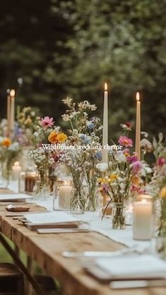 a long table with candles and flowers on it is set up for an outdoor dinner