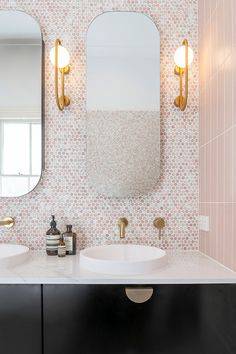 a bathroom with two sinks, mirrors and lights on the wall above them is shown