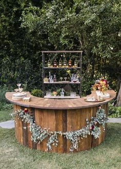 an outdoor bar is decorated with greenery, candles and bottles on the outside table