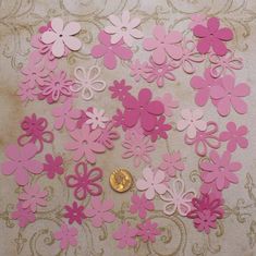 pink and white paper cut outs on a table with a gold coin in the middle