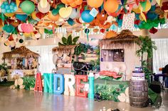 a room filled with lots of colorful balloons and decorations hanging from the ceiling above it