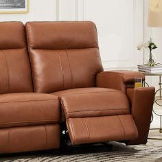 a brown leather reclining loveseat sitting on top of a rug