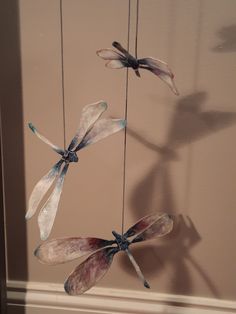 three glass dragonflies hanging from strings in a room