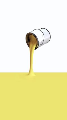 a yellow liquid pouring out of a white cup