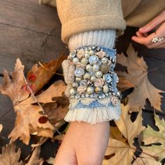 a woman's arm covered in buttons and beads, with her hand on the ground