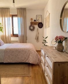 a bedroom with a bed, dresser and mirror on the wall next to a window