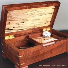 an open wooden box with a watch inside