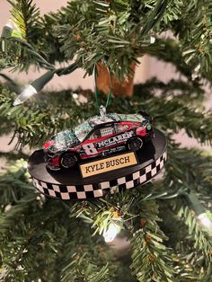 a christmas ornament hanging from a tree with a race car on it's side