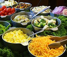 many bowls filled with different types of vegetables and cheese on display at a buffet table