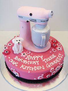 a pink birthday cake with an electric mixer on top