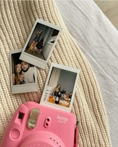 a pink camera sitting on top of a bed next to two pictures