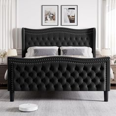 a black bed frame with buttons and studs on it in a white room next to two framed pictures