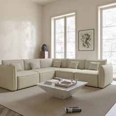 a living room with a large sectional couch and coffee table on the floor in front of two windows