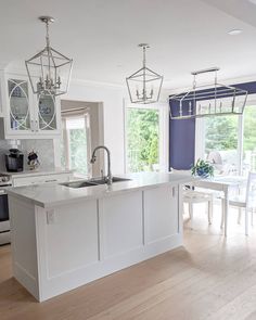 a kitchen with white cabinets and an island in front of a window that opens to the outside