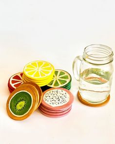 a glass jar filled with lemon slices next to some sliced oranges and kiwi