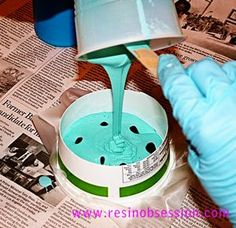 a person in blue gloves is pouring water into a bucket with a plastic container on it