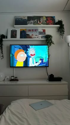 a flat screen tv sitting on top of a white dresser next to a plant in a pot