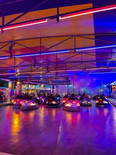 several bumper cars are lined up in a brightly lit indoor area with lights on the ceiling