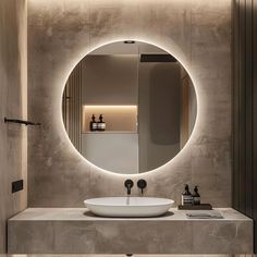 a bathroom sink with a round mirror above it and lights on the wall behind it