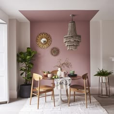 a dining room with pink walls and white rug on the floor, chandelier hanging from the ceiling