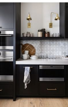 a kitchen with black cabinets and white counter tops, gold pulls on the door knobs