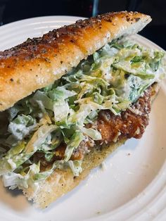 a sandwich with lettuce and meat is on a white plate, ready to be eaten