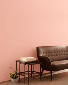 a brown leather couch sitting next to a table with a book on top of it