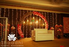 a white couch sitting in front of a wall covered with lights and flowers on it