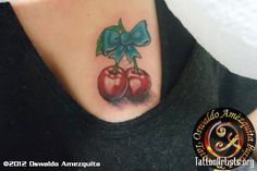 a woman's chest with two cherries and a bow tattoo on her neck