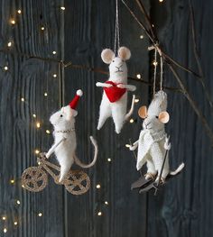 three mice hanging from a tree with lights in the background