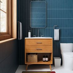 a bathroom with blue tile and wooden cabinet, toilet and sink in the foreground