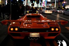 an orange sports car is parked on the street