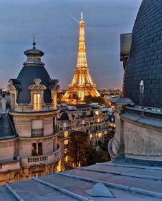 the eiffel tower is lit up at night in paris, with other buildings surrounding it