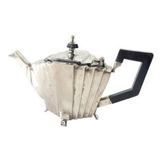 a silver teapot with black handles on a white background