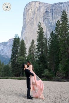 a man and woman are holding each other in front of a mountain