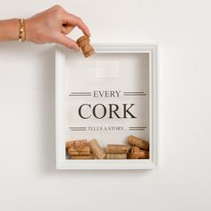 a person holding a cork in front of a white box that says every cork tells a story