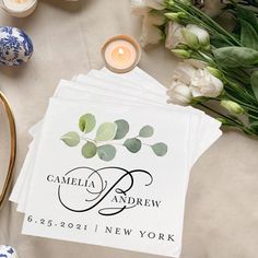 three personalized napkins on top of each other with flowers and candles in the background