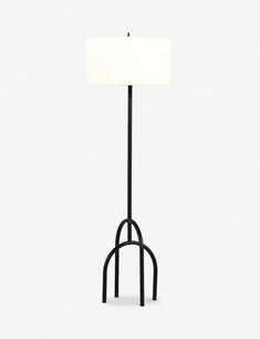 a floor lamp with a white shade on it's side and a black stand