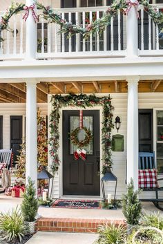 a front porch decorated for christmas with wreaths and decorations