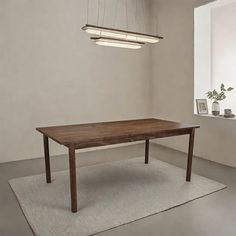 a wooden table sitting on top of a rug next to a white wall and window