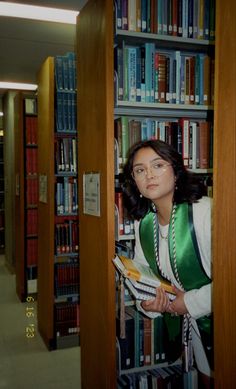 a woman standing in front of a book shelf filled with books