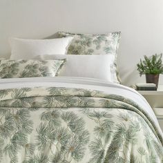 the comforter is made up with pine needles and white pillows on top of it