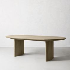 an oval wooden table sitting on top of a white floor