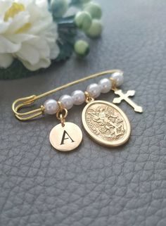 the initial charm bracelet is next to a white flower and a gold plated cross