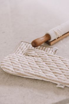 a brush and cloth sitting on a counter top next to a wooden spatula in the shape of an oven mitt