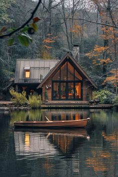 a small boat floating on top of a lake next to a house in the woods