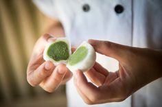 a person holding two pieces of food in their hands with a green substance on top