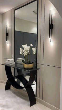 a black and white table with flowers on it in front of a large wall mirror