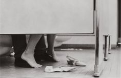 two people standing on the floor with their feet up against a wall and one person's shoes laying on the ground